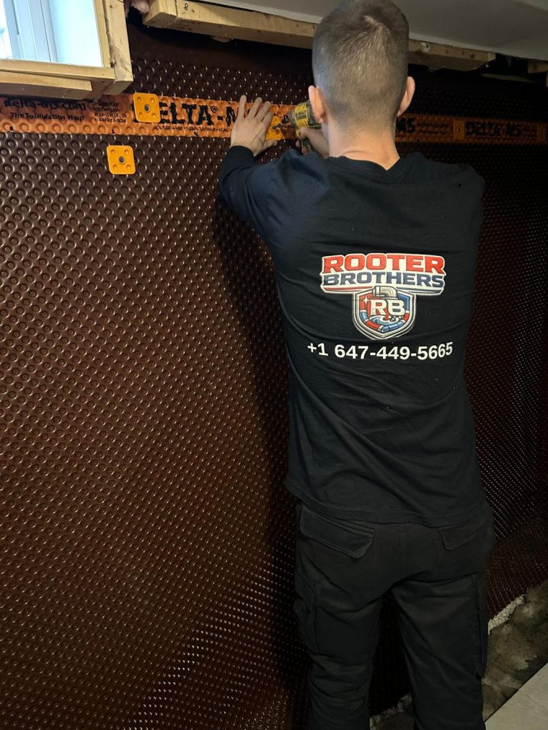 Rooter Brothers technician installing a basement waterproofing membrane in Toronto