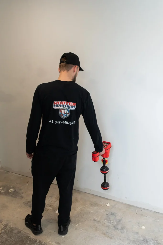 Plumber locating a buried drain line in a Richmond Hill basement